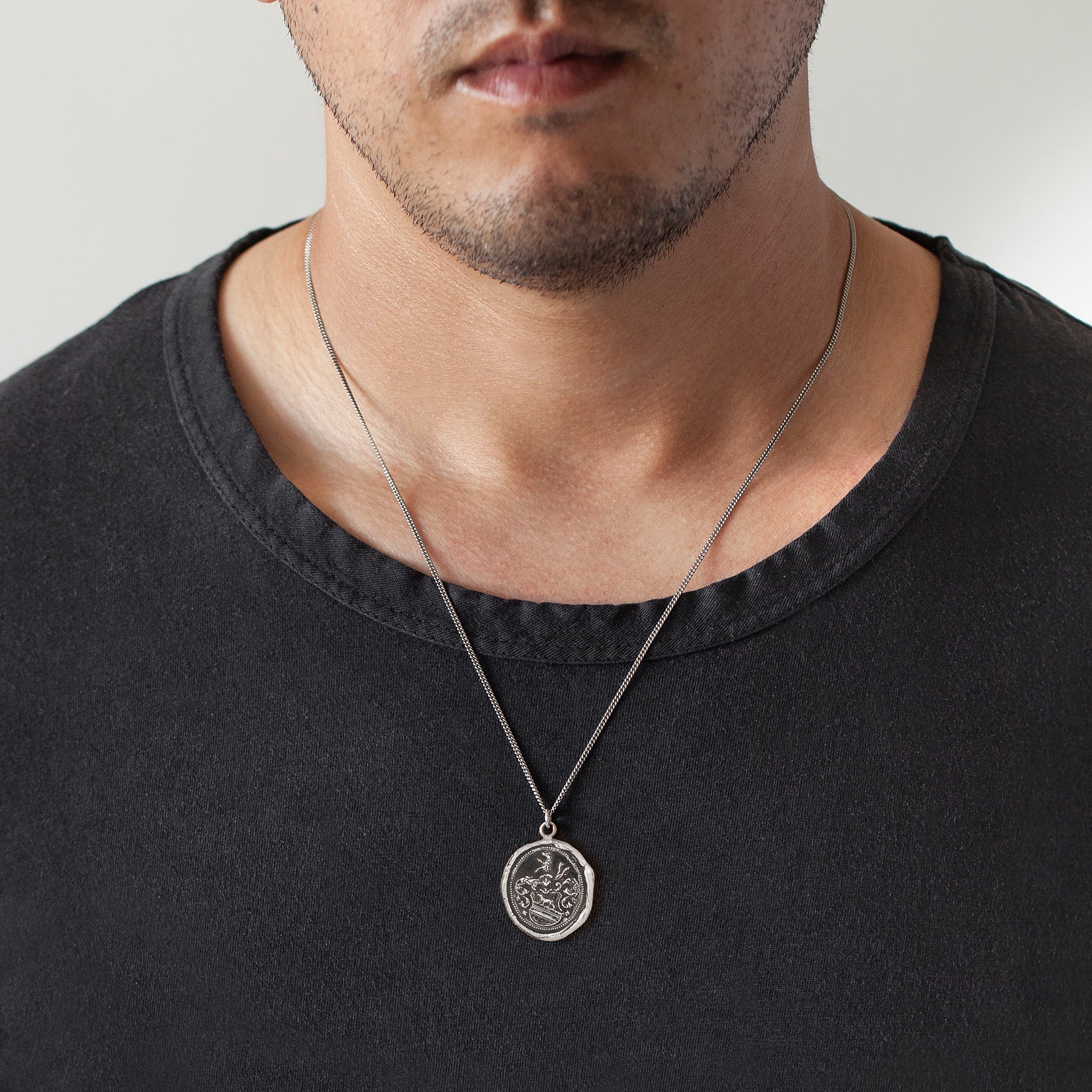 A close up of a model wearing Pyrrha's Oxidized Silver Heart of the Wolf talisman.