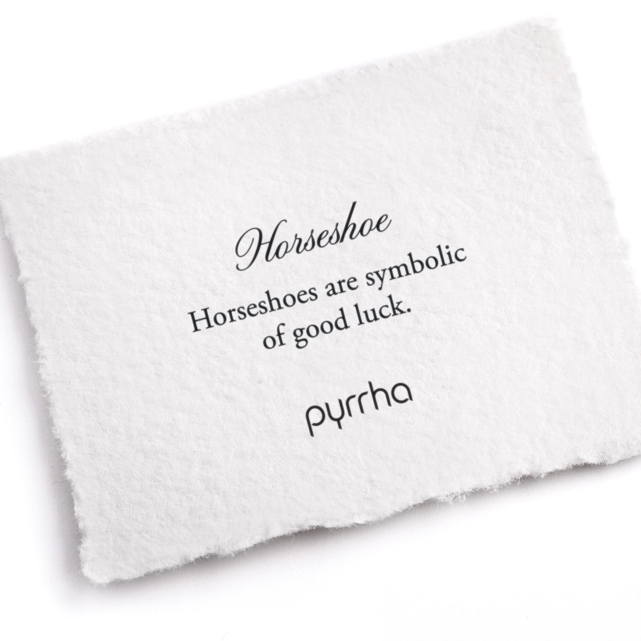 A hand-torn, letterpress printed card describing the meaning for Pyrrha's Horseshoe Symbol Charm