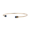 A 14k gold bangle made to hold charms capped with a semi precious sapphire stone representing loyalty.