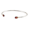 An open silver bangle capped with semi precious stones promoting clarity