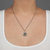 A close up of a model wearing Pyrrha's Oxidized Silver Heart Print Talisman Necklace.
