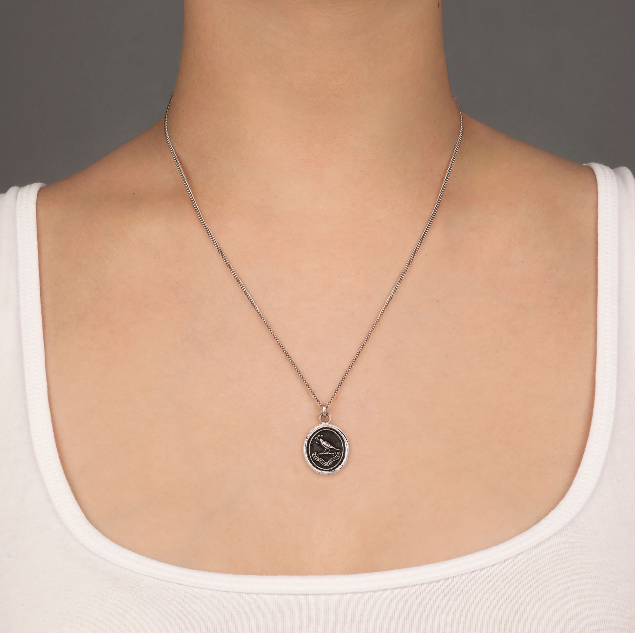 A close up of a model wearing Pyrrha's gratitude talisman on a Oxidized Silverchain.