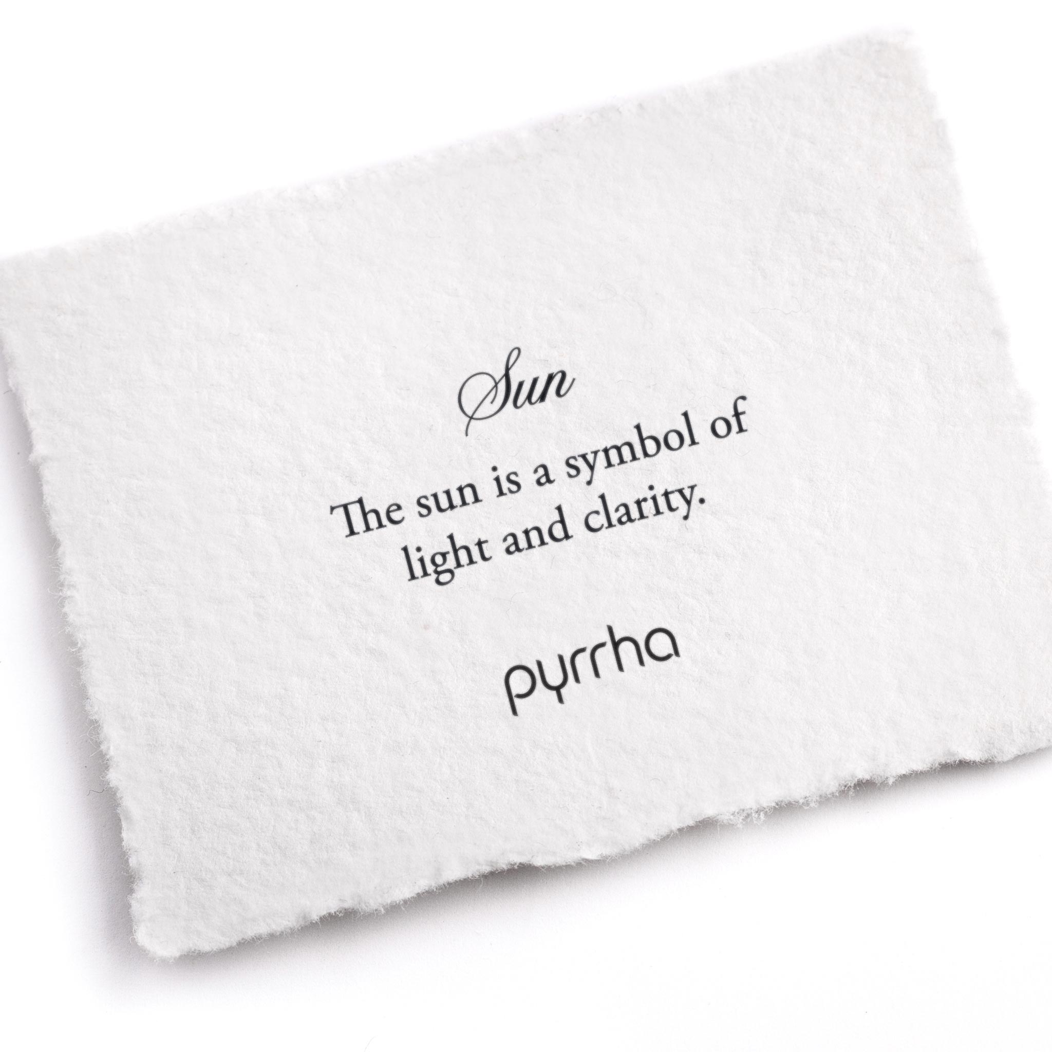 A hand-torn, letterpress printed card describing the meaning for Pyrrha's Sun Symbol Charm