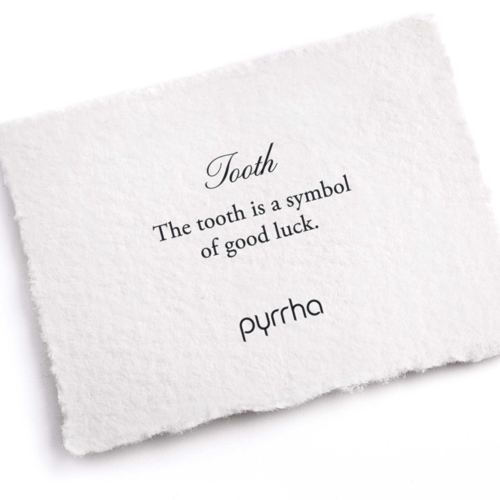 A hand-torn, letterpress printed card describing the meaning for Pyrrha's Tooth Symbol Charm