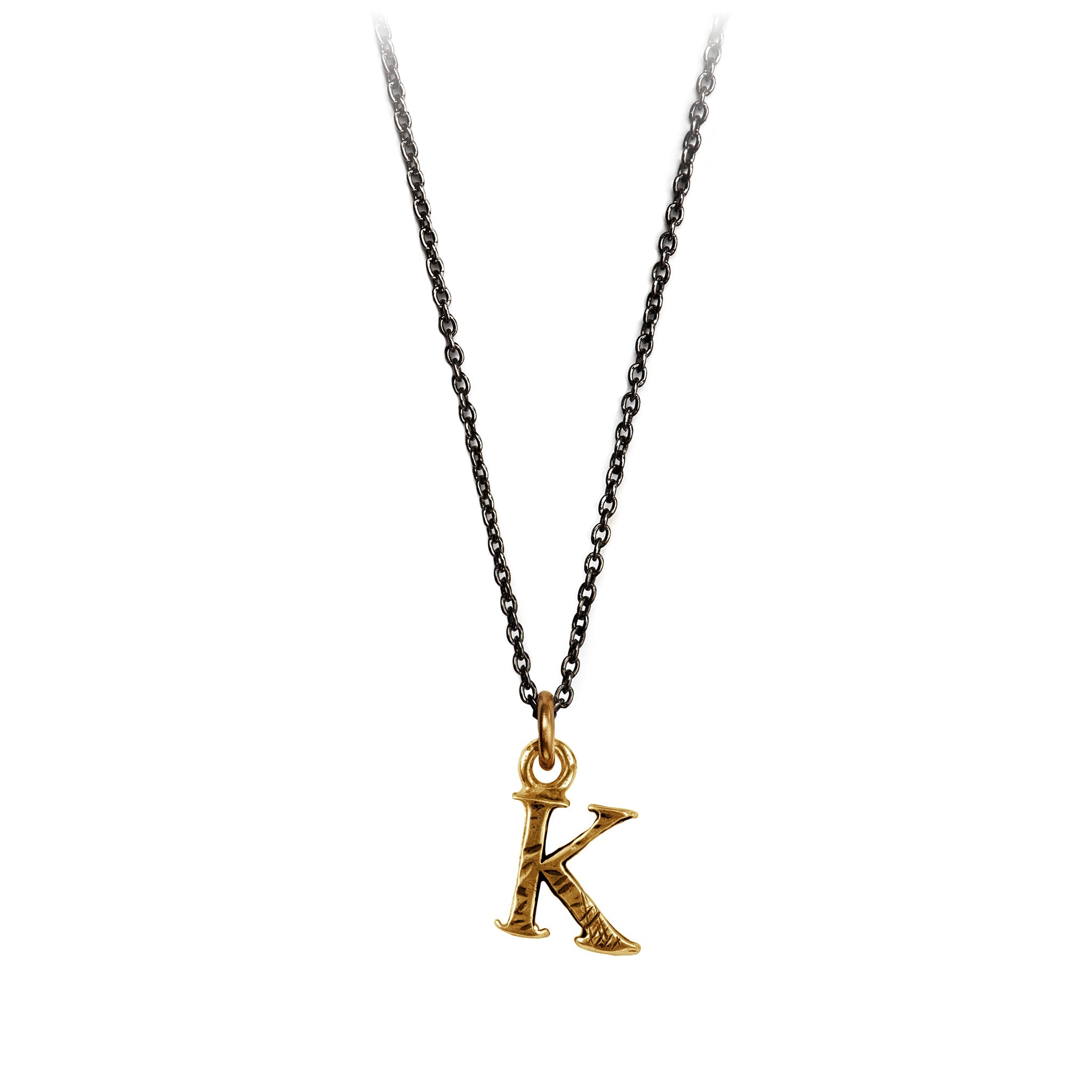 A bronze "K" charm on a blackened sterling silver chain.