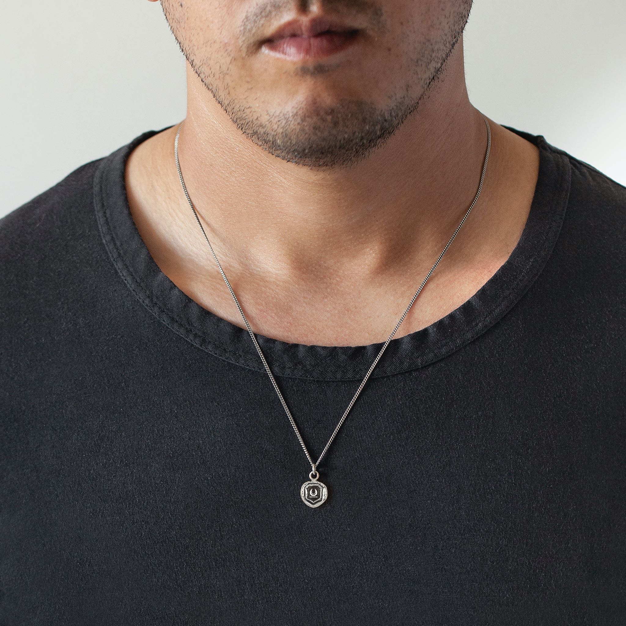 A close up of a model wearing Pyrrha's Oxidized Silver New Beginnings Talisman Necklace.