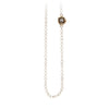 A necklace of hand strung ivory white pearls with a 14k gold bezel set grey diamond.
