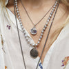 A close up of a model showing off a selection of Pyrrha talismans and charms.