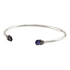 An open silver bangle capped with semi precious stones promoting creativity