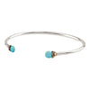 An open silver bangle capped with semi precious stones promoting friendship