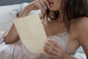 A close up of a model wearing our Solitaire 14K Gold Partner Ring and holding a sheet of paper.