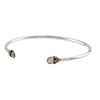 An open silver bangle capped with semi precious stones promoting harmony