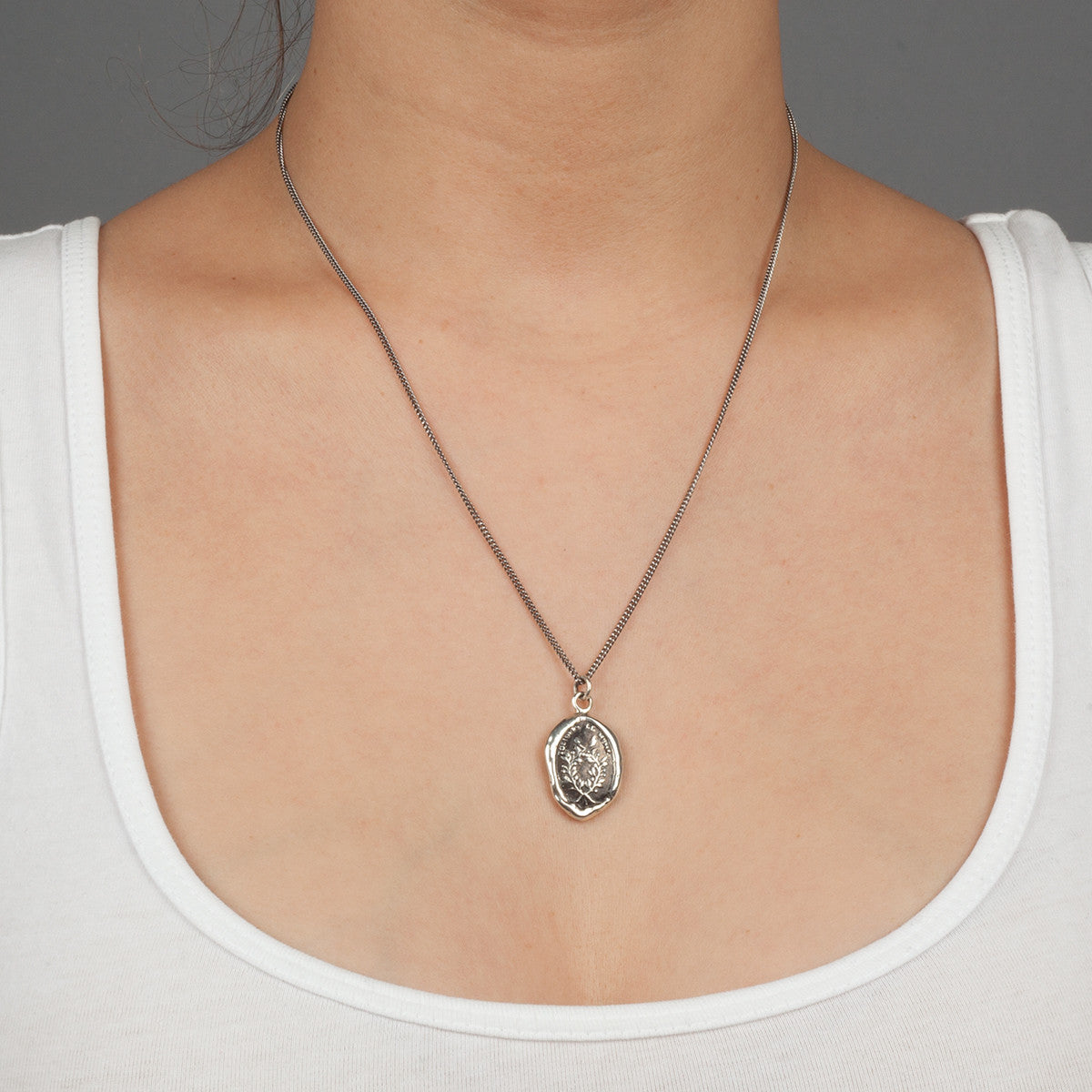 A close up of a model wearing Pyrrha's sterling silver Integrity Talisman Necklace.