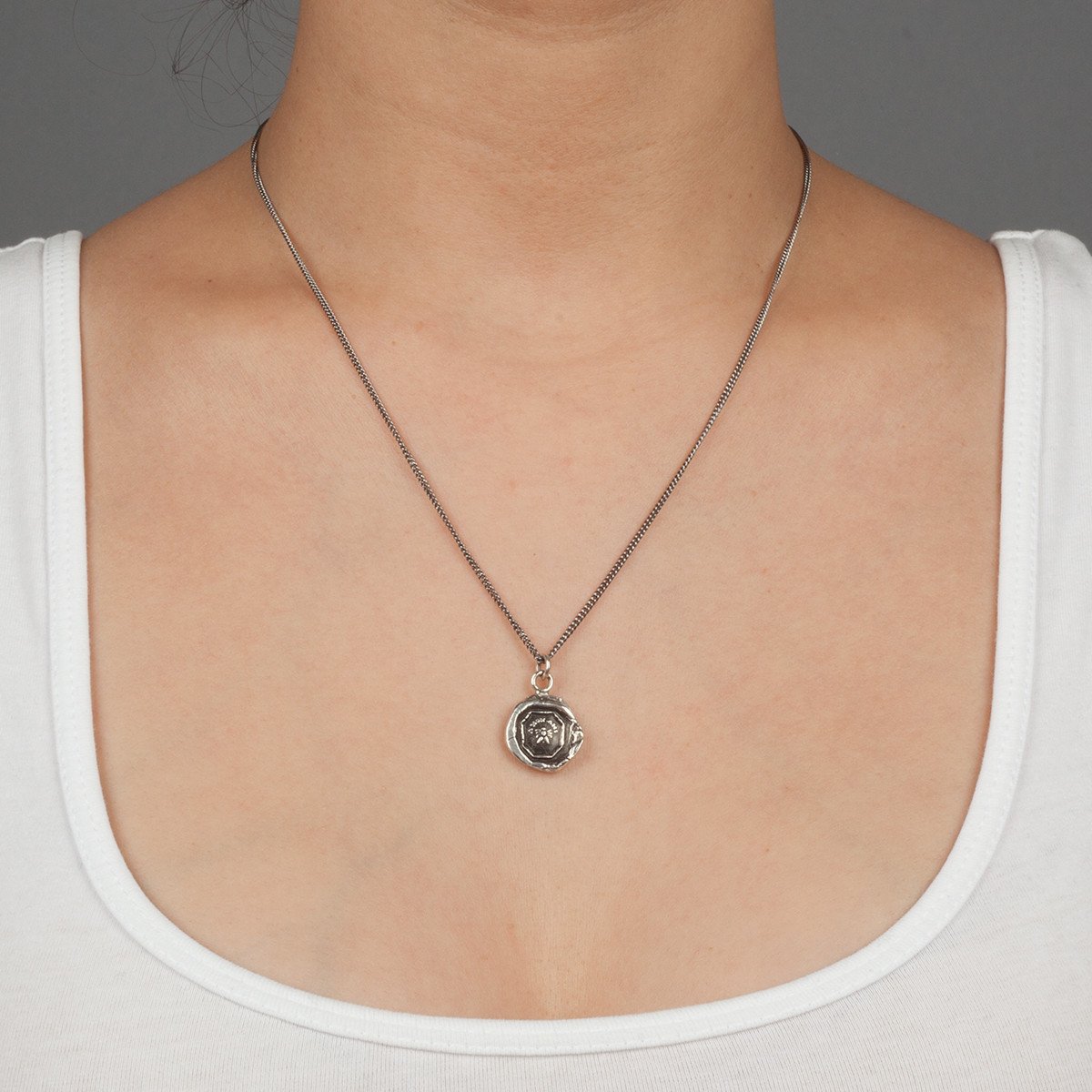 A close up of a model wearing Pyrrha's Oxidized Silver My Friend Talisman Necklace.