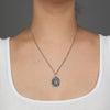 A close up of a model wearing Pyrrha's Oxidized Silver Love Conquers All Talisman Necklace.