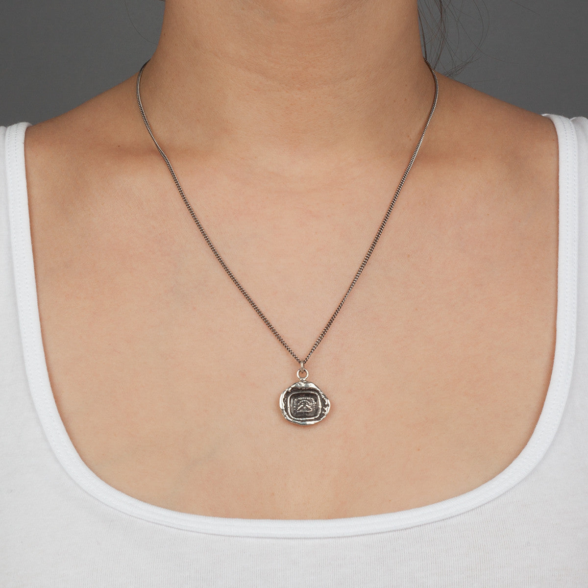 A close up of a model wearing Pyrrha's sterling silver Rare Birds Talisman Necklace.