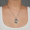A close up of a model wearing Pyrrha's Oxidized Silver Three Graces Talisman Necklace.