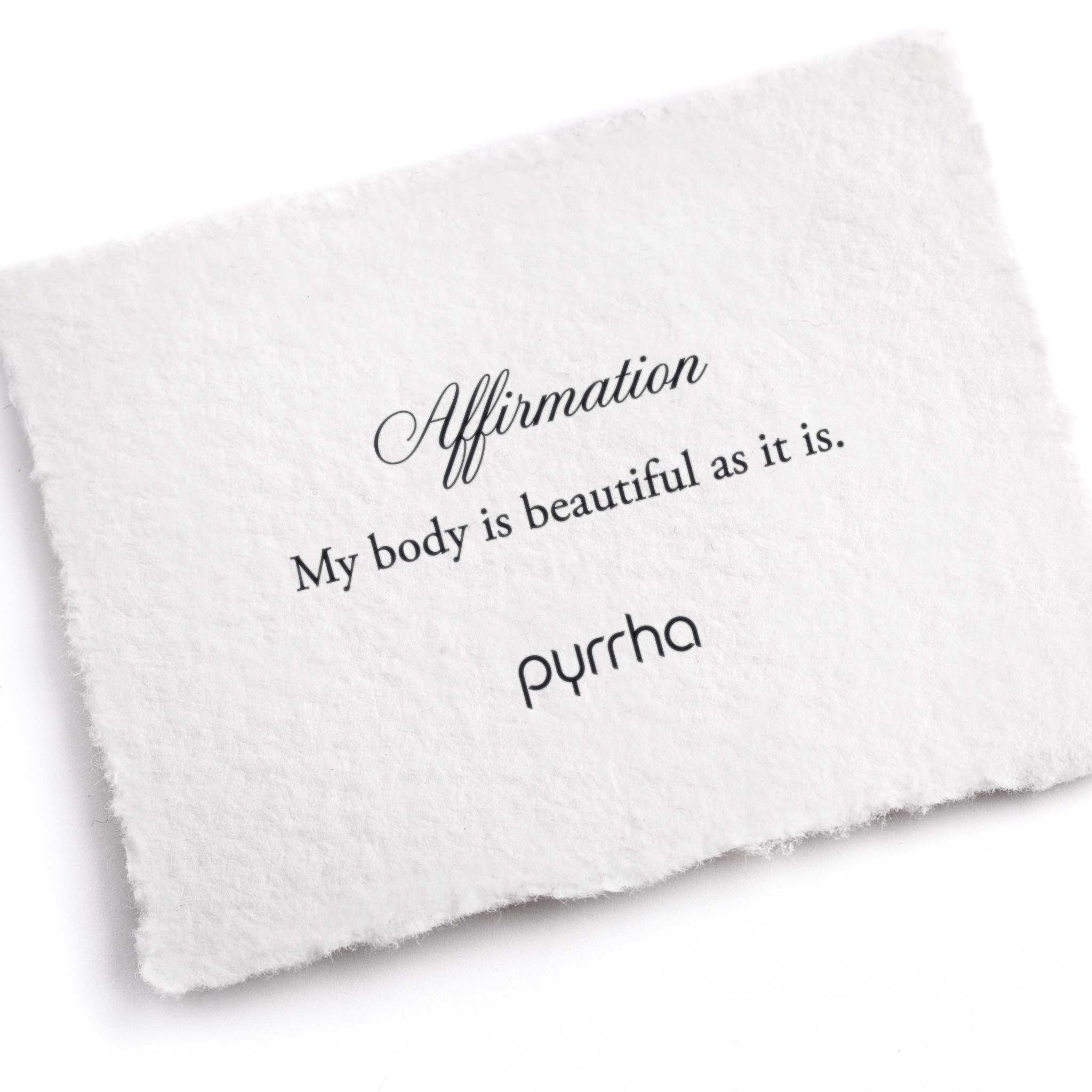 A hand-torn, letterpress printed card describing the meaning for Pyrrha's My Body Is Beautiful As It Is Affirmation Talisman Necklace