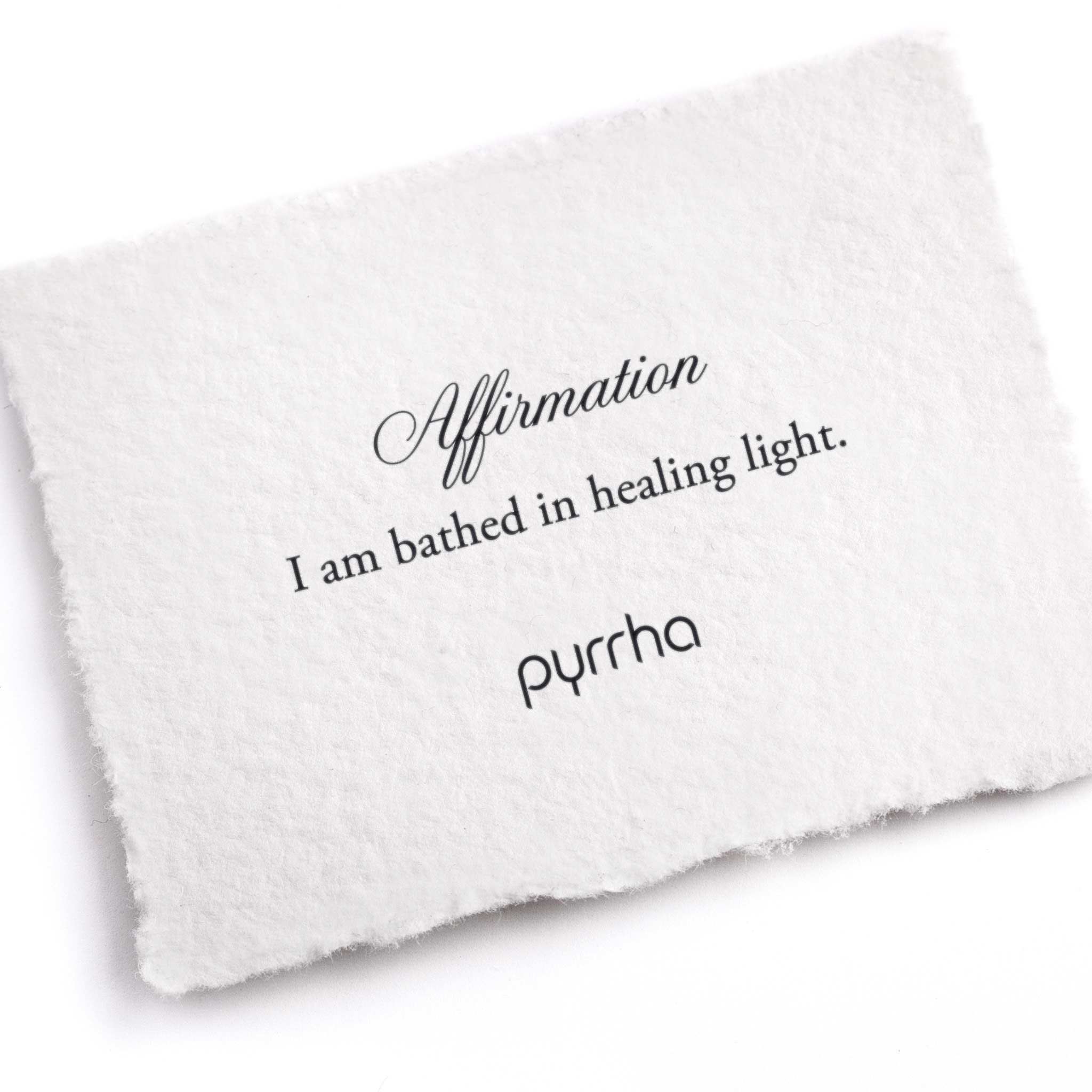 A hand-torn, letterpress printed card describing the meaning for Pyrrha's I Am Bathed In Healing Light Affirmation Talisman Necklace