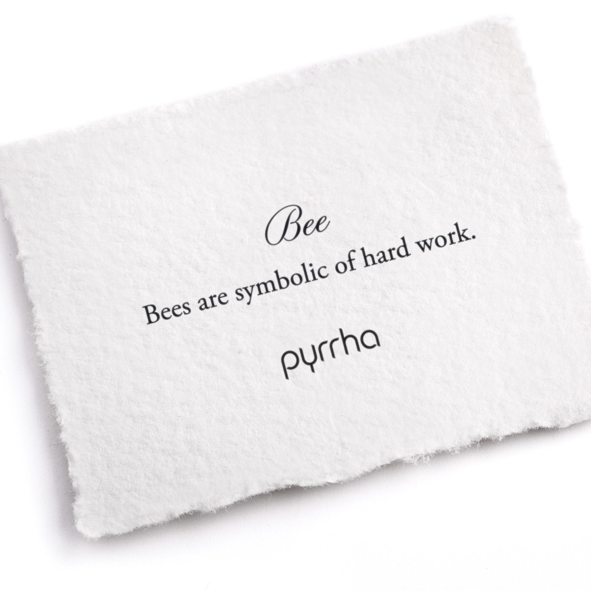 A handtorn cotton card describing the meaning for our Bee 14K Gold Symbol Charm Bracelet.
