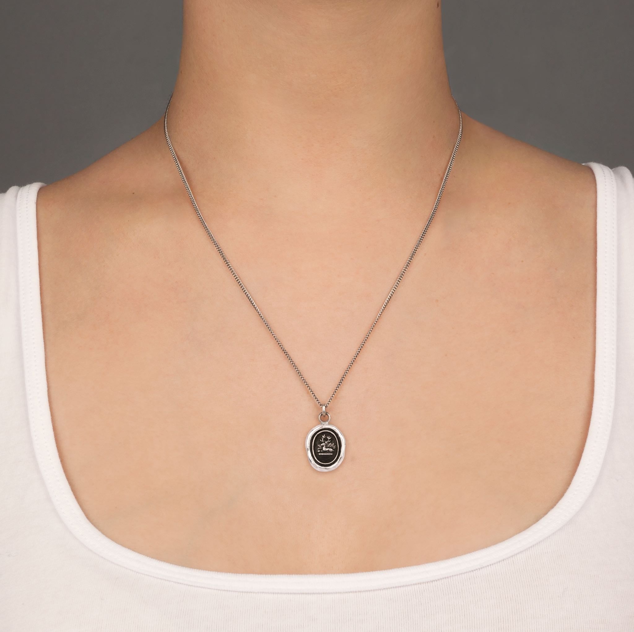 A close up of a model wearing Pyrrha's grounding talisman on a Oxidized Silver chain.