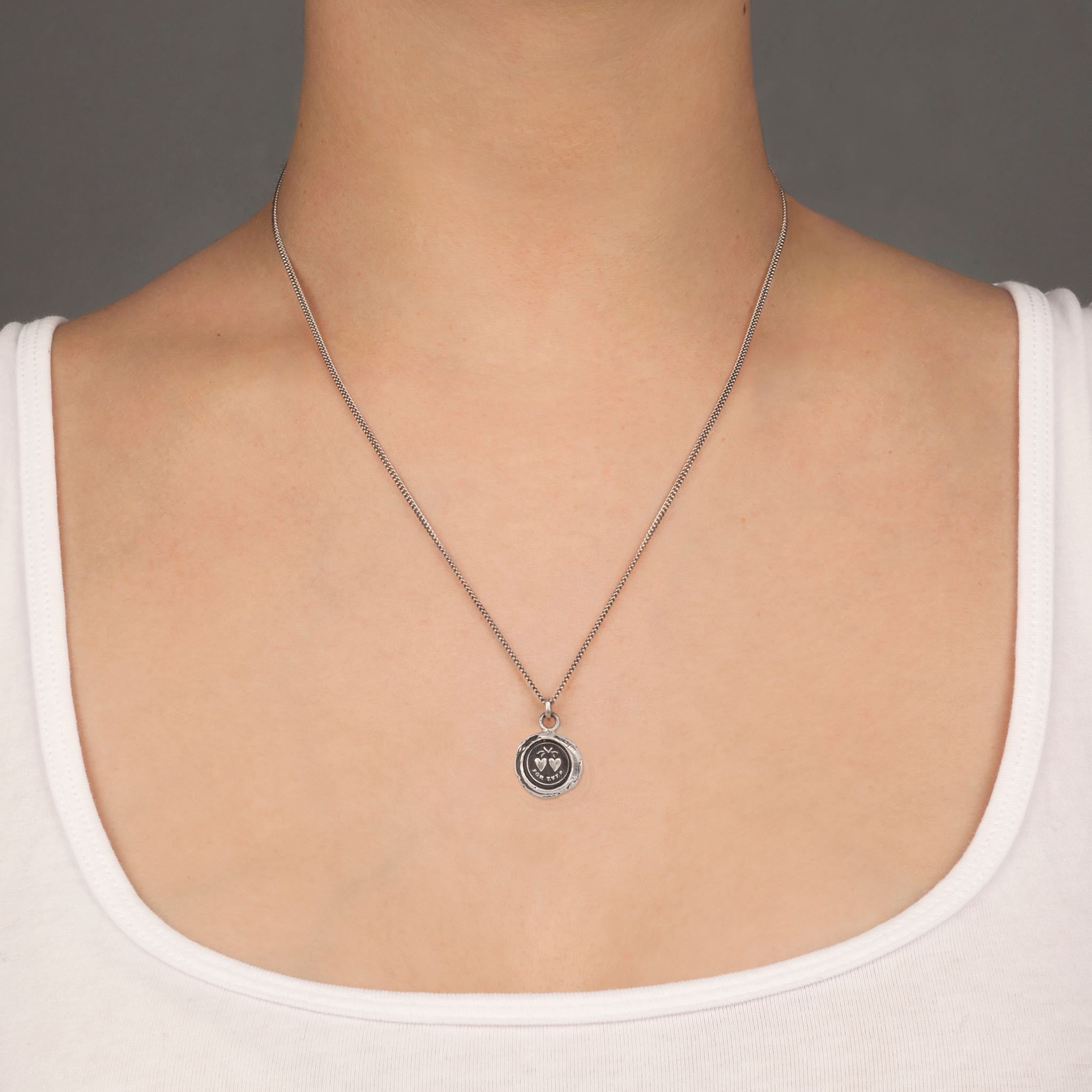 A close up of a model wearing Pyrrha's Oxidized Silver Hearts Talisman Necklace.