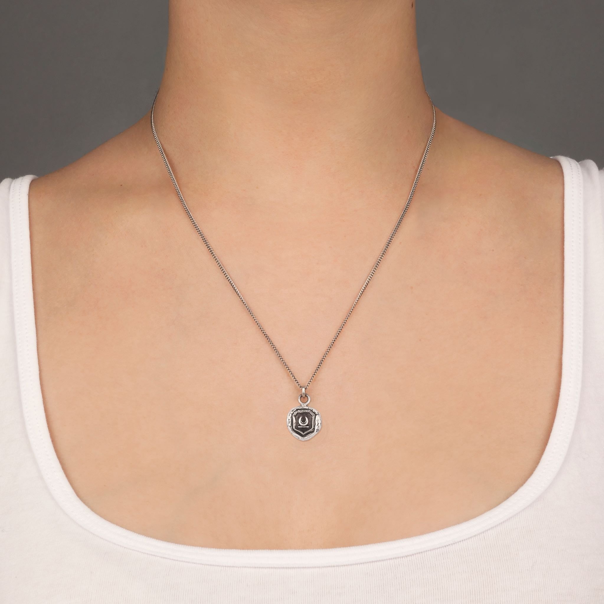 A close up of a model wearing Pyrrha's Oxidized Silver New Beginnings Talisman Necklace.