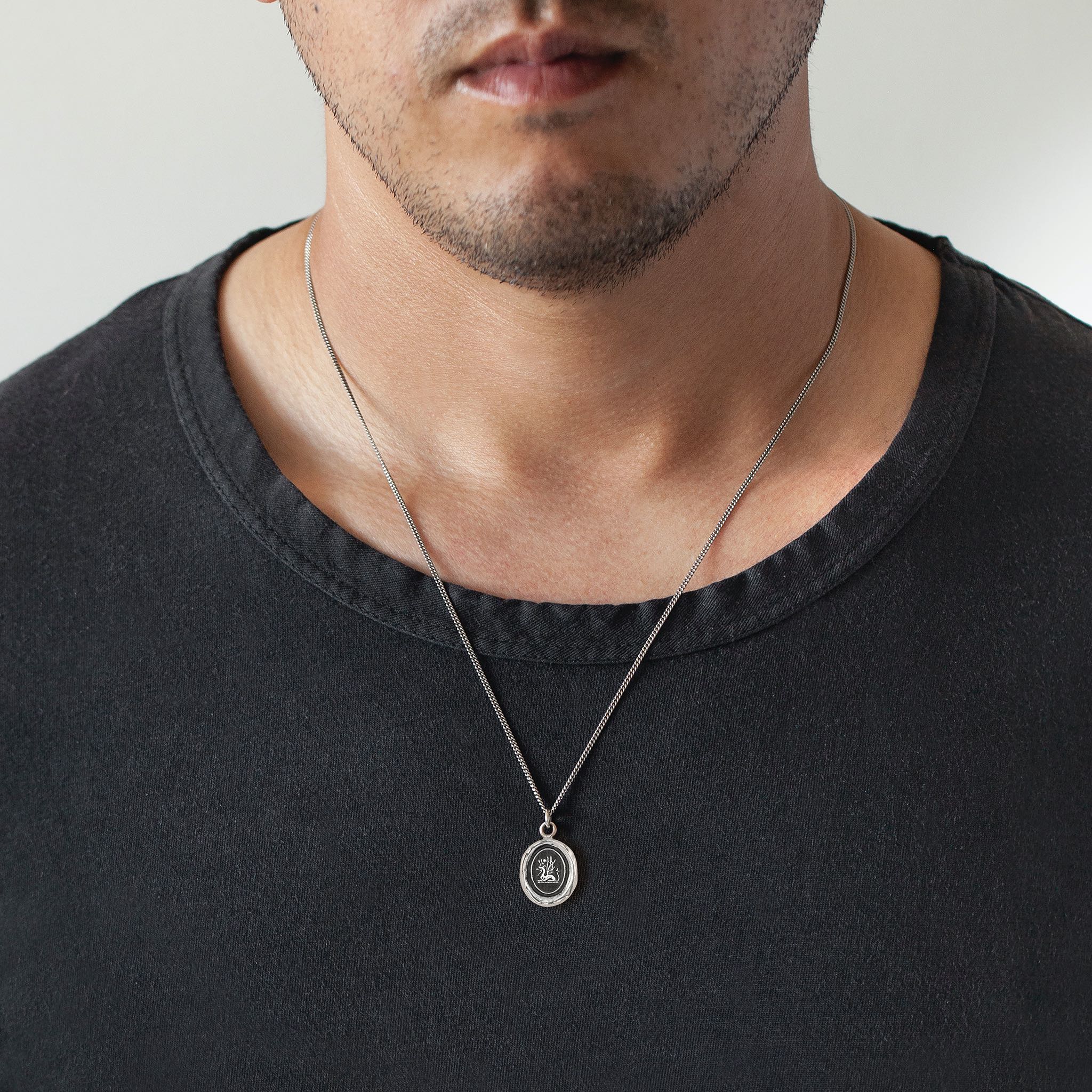 A close up of a model wearing Pyrrha's Oxidized Silver Protection Talisman Necklace.