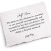 A hand-torn, letterpress printed card describing the meaning for Pyrrha's Self-Love 14K Gold Talisman