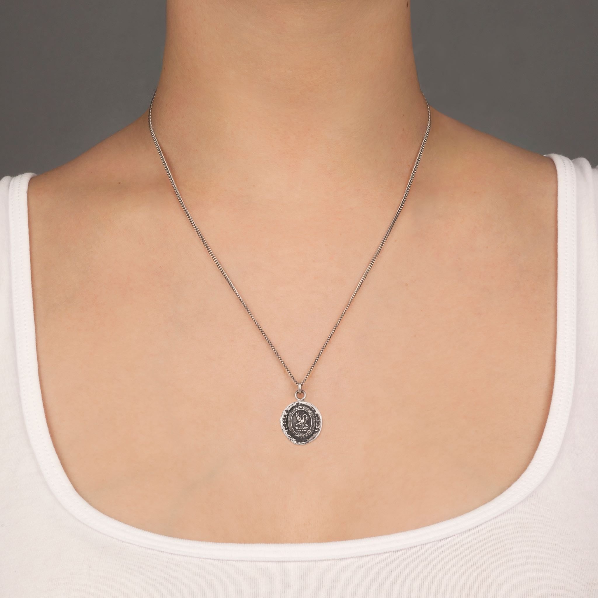 A close up of a model wearing Pyrrha's Oxidized Silver Selflessness Talisman Necklace.