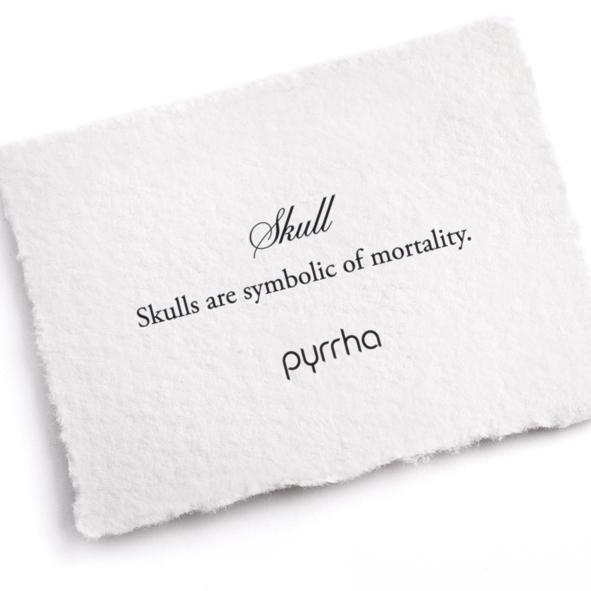 A handtorn cotton card describing the meaning for our Skull 14K Gold Symbol Charm Bracelet.