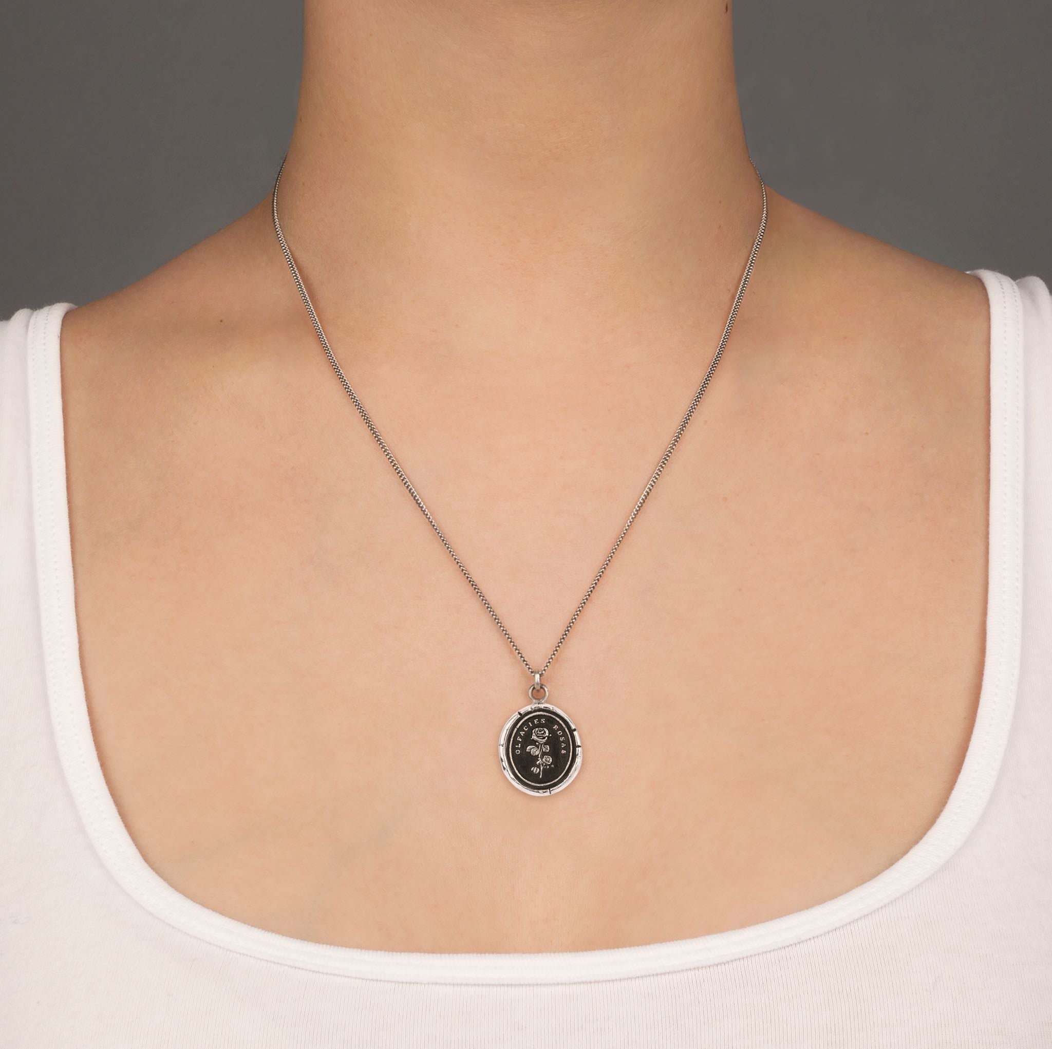 A close up of a model wearing Pyrrha's slow down talisman on a Oxidized Silver chain.